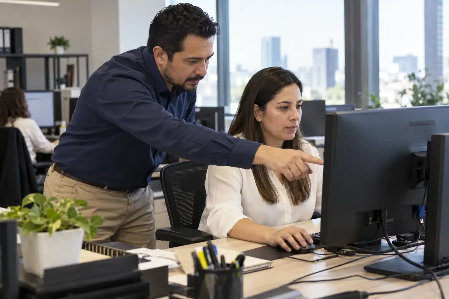Especialista de soporte revisando una computadora junto a una usuaria en una oficina